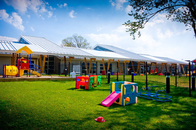 Play area with green grass, a small slide, a playground