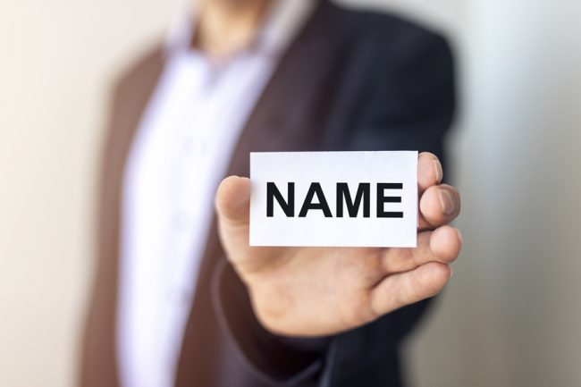 A businessman holding up a sign with the word Name on it