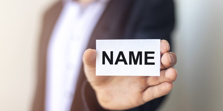 A businessman holding up a sign with the word Name on it